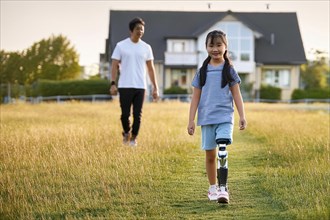 Girl with prosthetic leg walks happily on a country lane, father follows in the background, ai