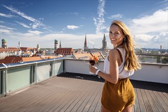 A woman stands on a roof terrace with a view of a cityscape in sunny weather, ai generated, KI