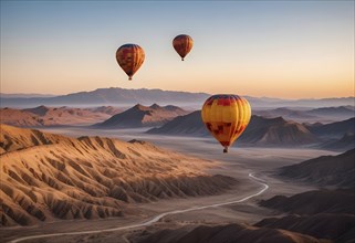 Three hot air balloons drifting over a desert landscape at sunrise with mountains in the distance,