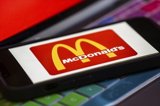 In this photo illustration, McDonald's logo is displayed on a smartphone with a laptop display