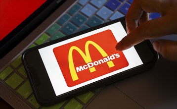 In this photo illustration, McDonald's logo is displayed on a smartphone with a laptop display