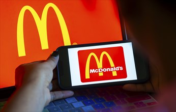 In this photo illustration, McDonald's logo is displayed on a smartphone with a laptop display