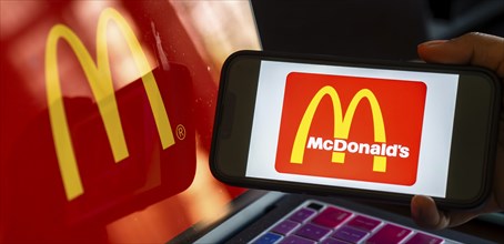 In this photo illustration, McDonald's logo is displayed on a smartphone with a laptop display