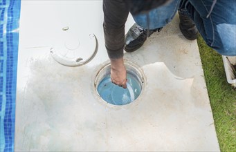 Person cleaning pool filter skimmer basket. Cleaning and maintenance of the swimming pool skimmer