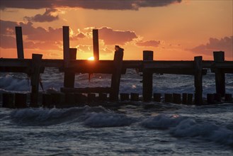 Sunset at the Baltic Sea with an old jetty in the foreground and dark clouds in the sky, Baltic Sea