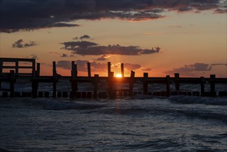 Sunset at the Baltic Sea with an old jetty in the foreground and dark clouds in the sky, Baltic Sea