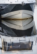 The bow of a ship is reflected in the Tanger river at the harbour at the mouth of the Elbe,