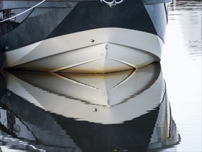 The bow of a ship is reflected in the Tanger river at the harbour at the mouth of the Elbe,