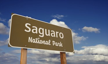 Saguaro national park (arizona) road sign against blue sky and clouds