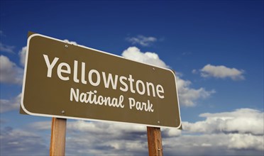 Yellowstone national park (wyoming, montana, idaho) road sign against blue sky and clouds