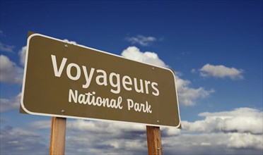 Voyageurs national park (minnesota) road sign against blue sky and clouds