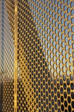 Aluminum composite panels or cladding with perforated sheets on modern building facade on sunset,