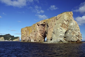 Large rocky cliffs in the sea under a blue sunny sky, Rock of Perce, Perce, St. Lawrence River,