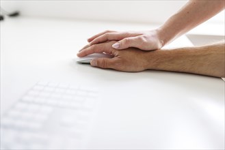 Topic: sexual violence in the workplace. A woman's hand lies on a man's hand at a desk in Berlin,