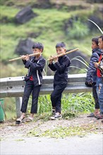 Vietnamese boys playing traditional flutes in the northern mountains, Ha Giang province, Vietnam,