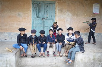 Vietnamese boys in traditional clothes and with traditional flutes playing with their mobile