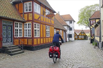 Cyclist riding through a picturesque cobblestone street in an old town with colourful half-timbered