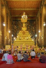 Worshippers oin front of Phra Buddha statue at the Phra Ubosot ordination hall, Wat Pho complex,