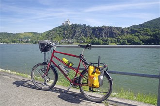 A bicycle stands in front of a railing with a view of the river and a castle on a hill, Middle