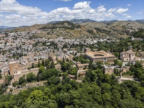 View of a city with historic buildings and lush vegetation in a hilly landscape, aerial view,