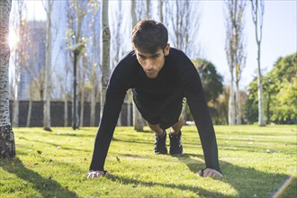 Close up of young man doing push-ups on a grass in the park