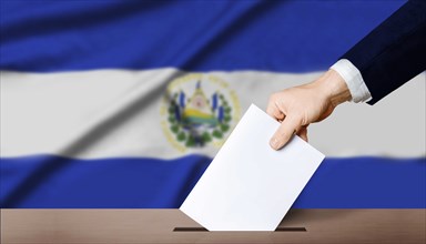 Hand holding ballot in voting ballot box with El Salvador flag in background. El Salvador