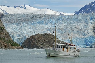 Small boat in front of the ice front of a glacier calving into the sea, Tracy Arm Fiord, Climate