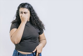 Latin woman covering nose from a bad smell isolated. Displeased girl holding her nose isolated.