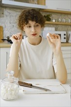 Brave woman looks at a piece of sugar wanting to reduce the amount of sweets in her food