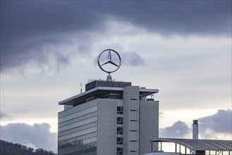 Mercedes star in front of dark clouds, office building at the headquarters of Mercedes-Benz Group