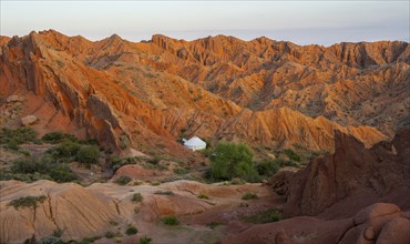 Yurt between red rocks, canyon of eroded sandstone formations, red and orange sandstone rocks,