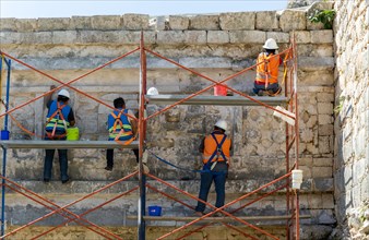 Workers maintaining stonework at The Nunnery, Edificio de las Monjas, Chichen Itza, Mayan ruins,