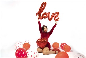 Studio portrait of beautiful young woman in red dress on white background holding a sign with the