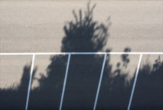 Drone shot, empty car park with shadows cast by trees, from above, structure, road traffic,