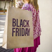 Close-up of a shopping paper bag with a Black Friday sign carried by a woman