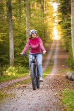 Woman on Ebike through the autumn forest, Black Forest, Gechingen, Germany, Europe