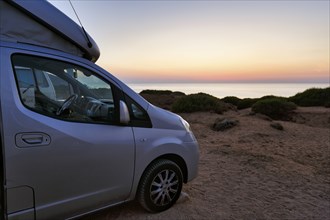 Campervan after sunset, motorhome on car park by the sea, mini camper with pop-up roof, opened