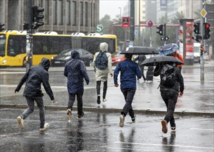 People in rain gear running across a street in heavy rainfall Berlin, 23 06 2023