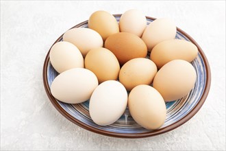 Pile of colored chicken eggs on plate on a gray concrete background. side view, close up