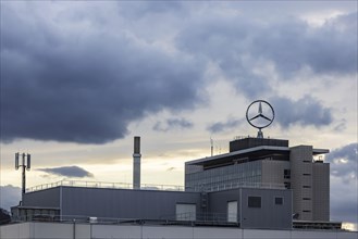 Mercedes star in front of dark clouds, office building at the headquarters of Mercedes-Benz Group