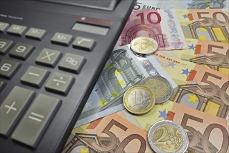 Euro banknotes and coins and pocket calculator