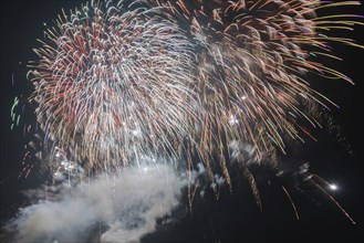 Colourful fireworks light up the night sky with sparkling lights and trails of smoke, symbolic