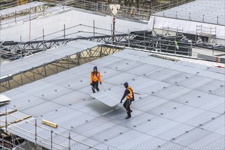 Construction workers transport part of a temporary roof. Construction site Stuttgart21. Stuttgart,