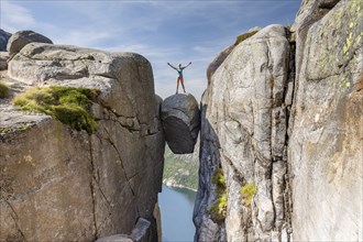 Woman standing on Kjeragbolten, jammed rock above the Lysefjord, Kjerag, Lysebotn, Rogaland,