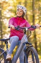 Woman sitting on Ebike through autumn forest, Black Forest, Gechingen, Germany, Europe