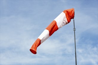 White-red windsock against blue sky, cloudy, wind vane, Germany, Europe