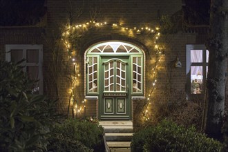 Front door of Frisian house illuminated by Christmas lights in village Toftum on the island Föhr,