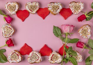 Frame made of heart-shaped cupcakes, red hearts and roses, Valentine's Day, pink background