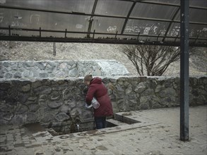 A woman fills drinking water at a public well. In the northern and eastern neighbourhoods of