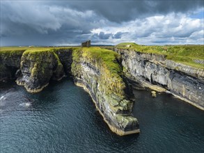 Aerial view of the ruined Castle of Old Wick surrounded by rugged cliffs on the North Sea coast,